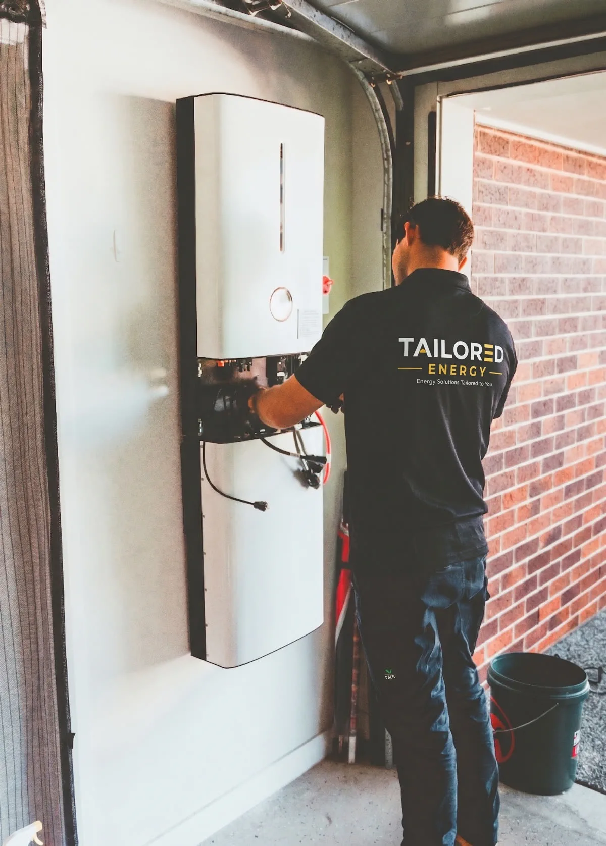 Tailored Energy technician installing a home battery in an Auckland garage